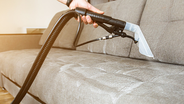 upholstery cleaner being used on grey sofa