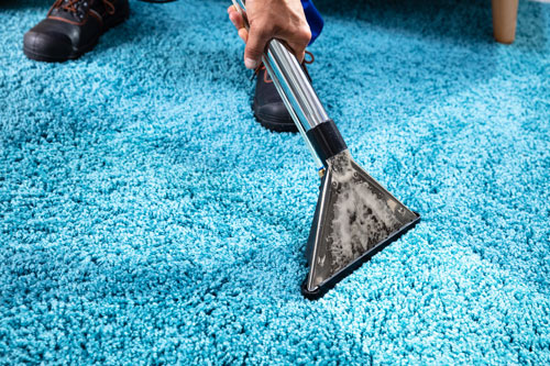 metal hose end of carpet cleaner being used on blue carpet